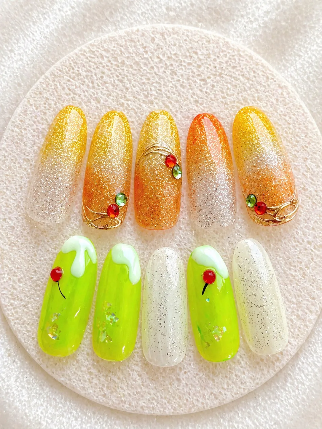オレンジラメとネオングリーン、ホワイトを組み合わせ、小さな赤と緑のパーツをあしらったネイル