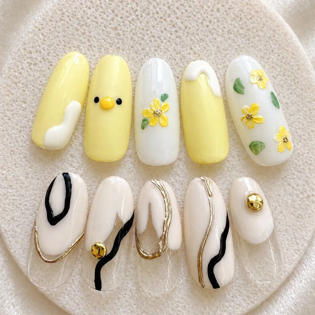 イエローとホワイトのスマイル・小花デザインと、ブラックとゴールドのうねりアートを組み合わせたネイル